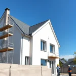 Construction dâune maison individuelle avec artisans sur chantier et structure en cours de rĂ©alisation